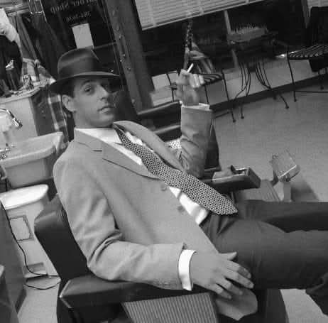 Farrell Stephens, founder of Pomade & Tonic, relaxed in a vintage suit and fedora enjoying a smoke in the barber chair